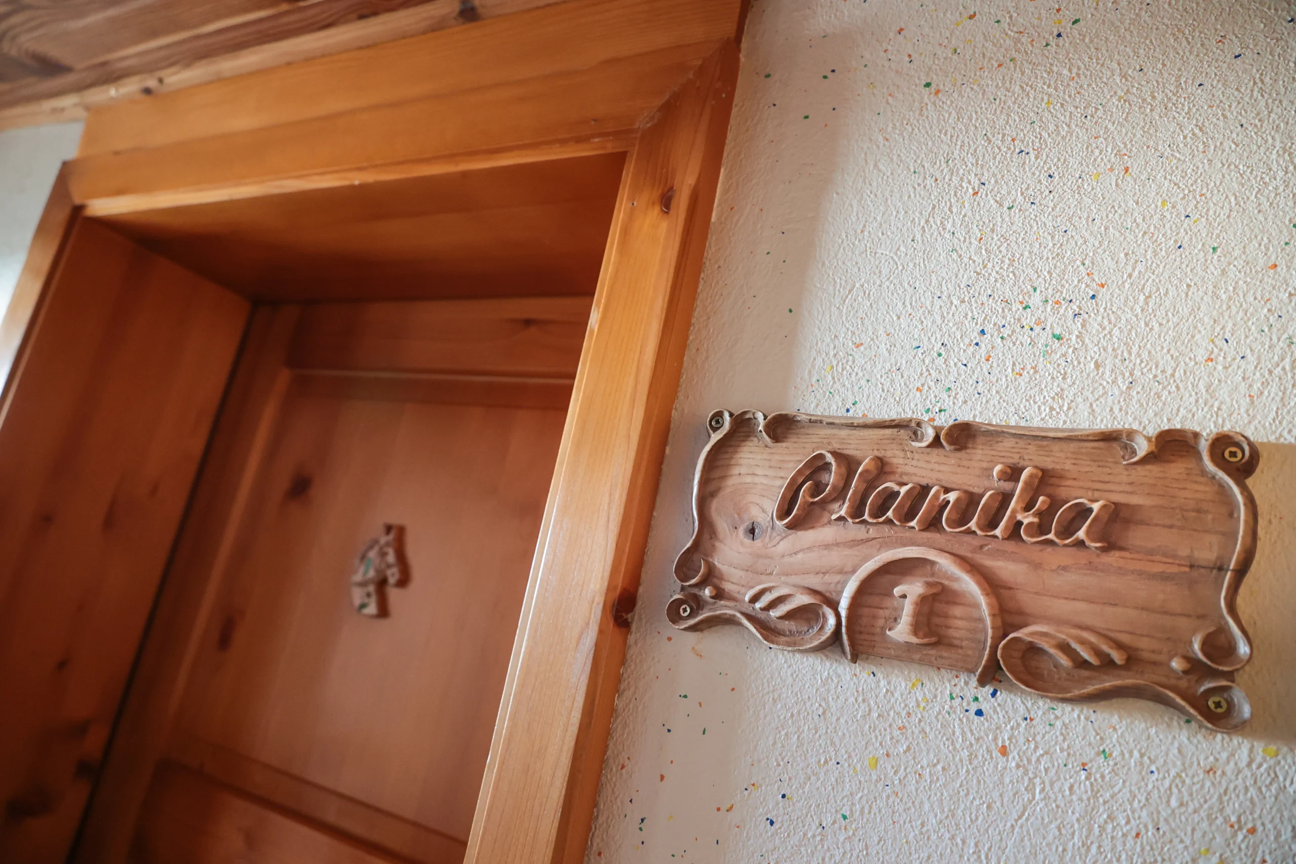 Wooden Planika name plaque beside the apartment entrance.